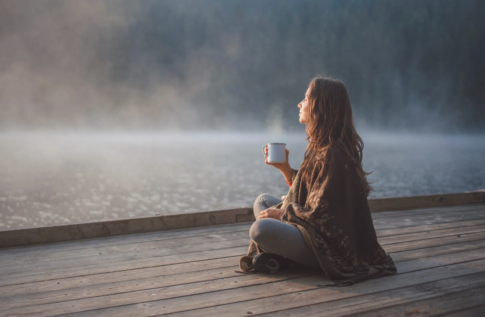 Adult sitting quietly beside a calm lake